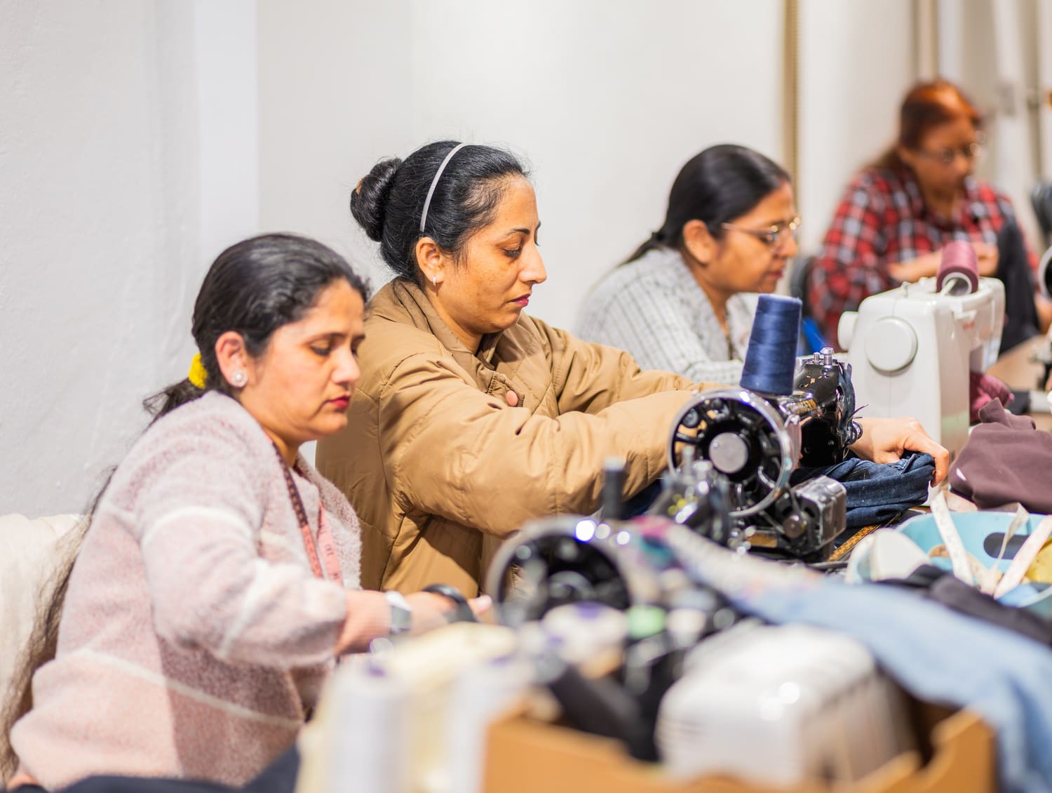 Des membres de l’atelier cousent côte à côte à leurs machines lors d’un événement de réparation.