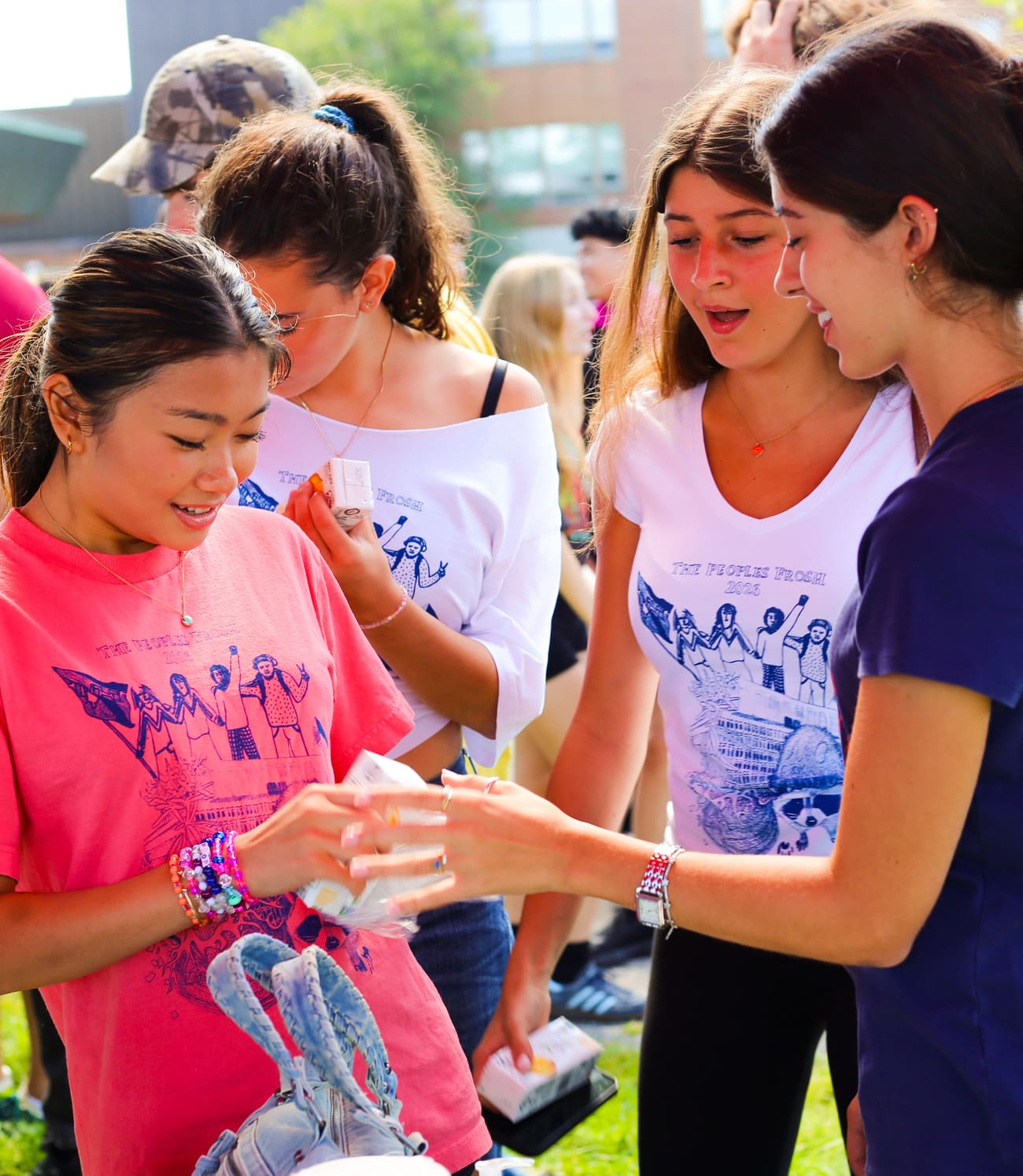 Des étudiantes au Peoples Frosh portent des t-shirts récupérés imprimés du même visuel, en rose, blanc et marine.