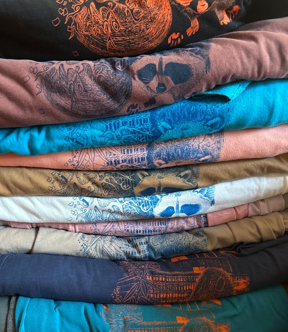 Une pile de t-shirts récupérés de couleurs différentes, tous imprimés du même visuel du Peoples Frosh.