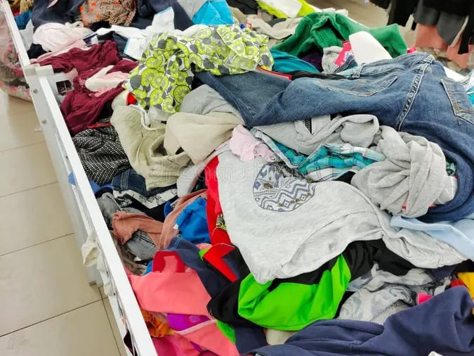 Un bac rempli de vêtements récupérés en friperie, prêts à être triés.